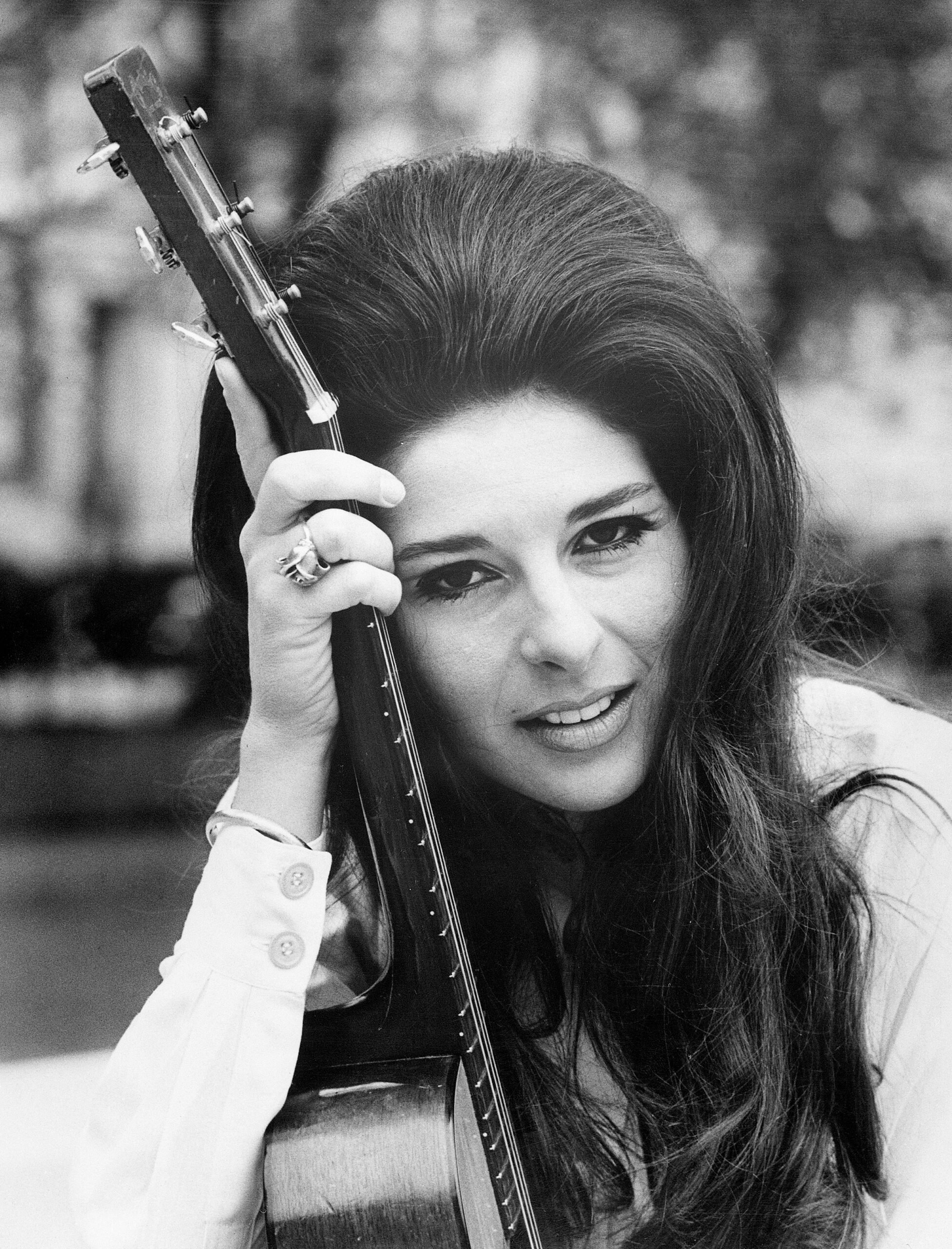 singing star pictured with her guitar in London, May 27, is Bobbie Gentry, who has arrived in the United Kingdom to film a BBC television and radio show. During her six weeks stay, Bobbie will cross the continent three times to star in the Olympia and Paris and film two TV shows, one in Hamburg, the other in Holland. Bobbie's multi-million selling hit, "Ode to Billie Joe," won her three Grammy Awards. She is shown in a head and shoulders shot, leaning her head on the neck of an acoustic guitar.