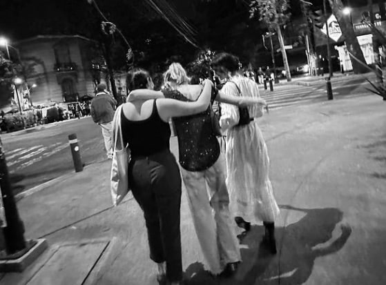 Tim McGraw and Faith Hill's daughters Gracie, Maggie, and Audrey went on their first "sister trip. Here, the three girls are photographed from the back with their arms around each other. The picture is in black and white.
