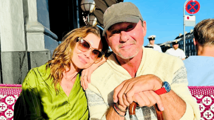 Tim McGraw and Faith Hill sit together at a restaurant in Copenhagen while Tim holds a cane in his hand.